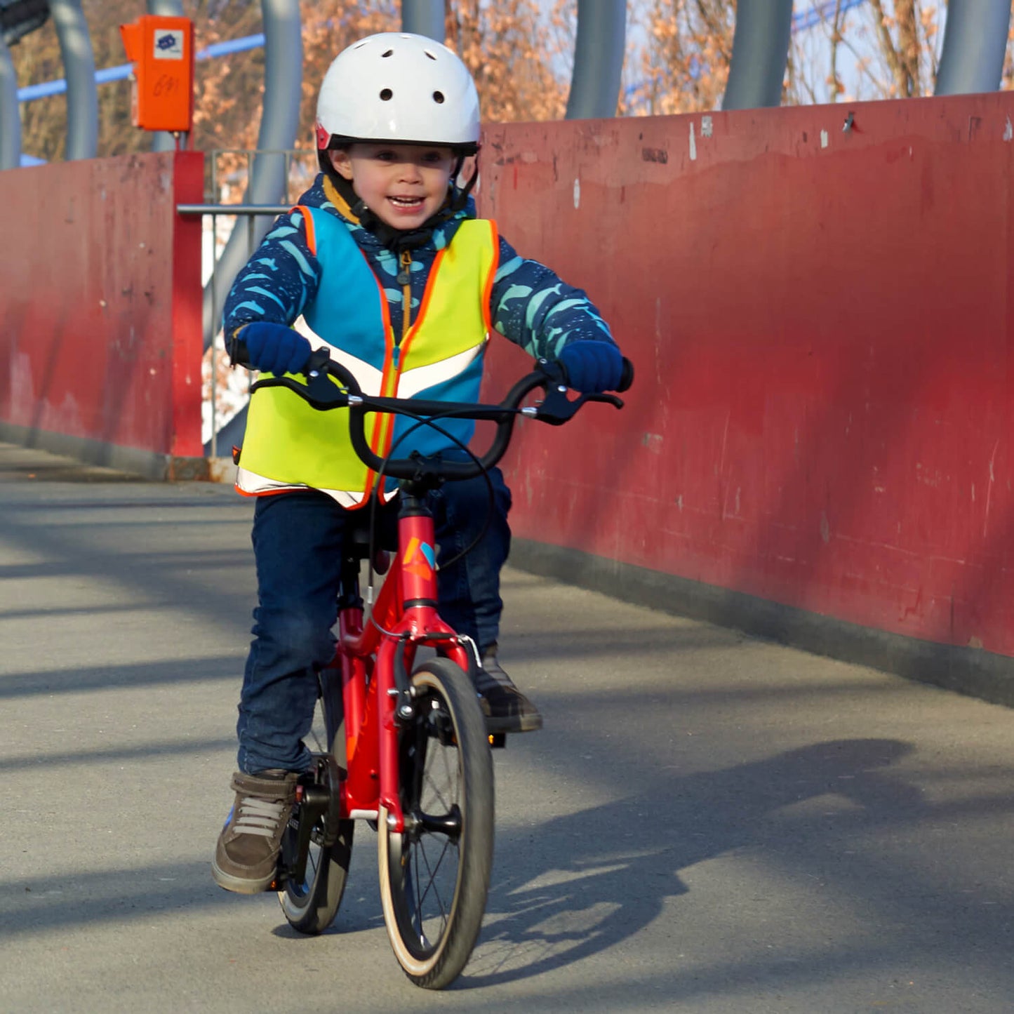 Junge mit Kinderwarnweste und Helm auf dem Fahrrad