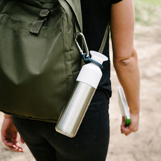 Dopper Trinkflasche mit Dopper Carrier am Rucksack befestigt.