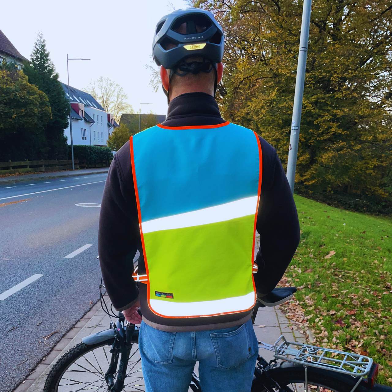 Fahrradfahrer mit reflektierendem Überwurf in gelb-rot von hinten