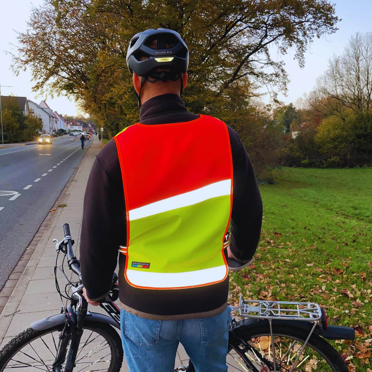 Fahrradfahrer mit reflektierendem Überwurf in gelb-rot von hinten